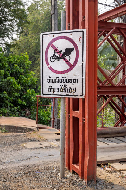 No rickshaw sign on a old wooden bridge crossing a river The Old French Bridge, Luang Prabang, Laos - March 18th 2023:  No rickshaw sign on the old wooden bridge which is from the time of the French occupation and are crossing the Nam Pak River in the former capital of Laos no rickshaws sign stock pictures, royalty-free photos & images