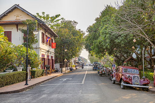 Sisavangvong Road, Luang Prabang, Laos - March 15th 2023: View up the street with tropical trees and architecture from the French occupation in the former capital of Laos