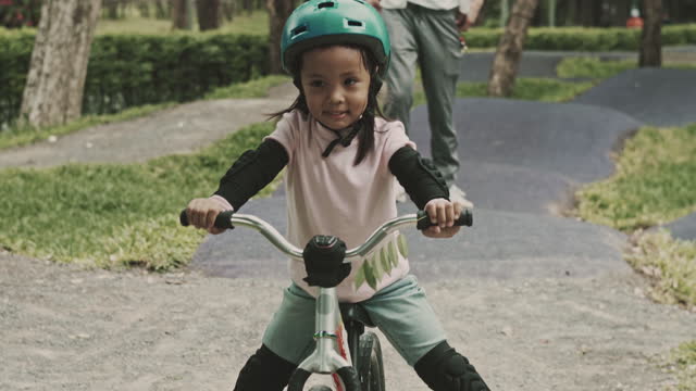 Little girl with helmets practicing balance bike