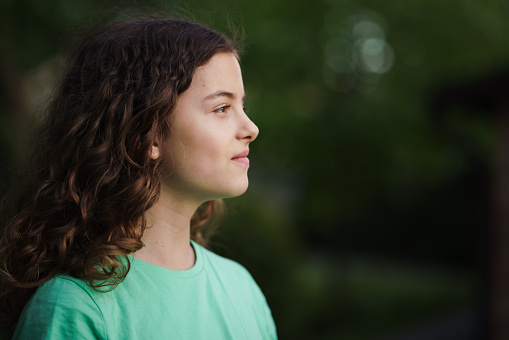 Side view portrait of teenage girl whit curly hair outdoors