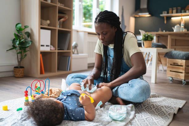 istock Mother Black ethnicity changing her baby boy diaper, during playtime 1495085202