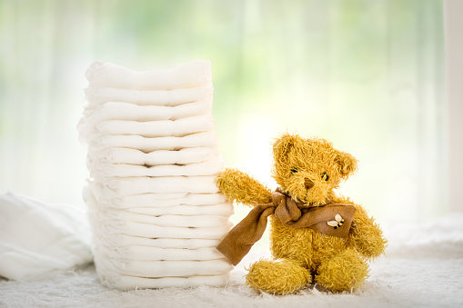 Stack of diapers or nappies with yellow teddy bear