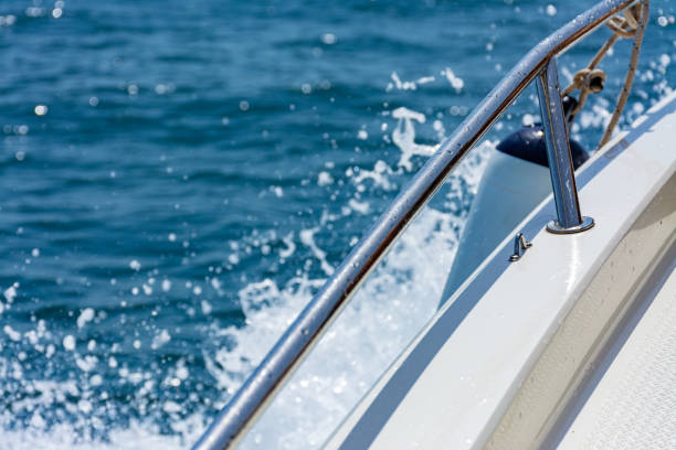Port edge of a small recreational boat sailing in the sea, with outboard protection and water splashing