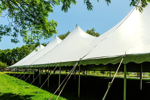 Large white event tent with four peaks held up by poles