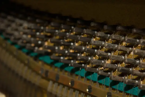 Repair of a stringed musical instrument. The interior of a piano with brass metal strings and a wooden mallet. Old fashioned musical instrument for performing music