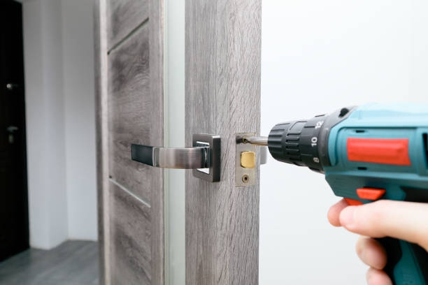 istock Handyman Fitting A New Door Using A Screwdriver At Home. Carpenter at lock installation with electric drill into interior wood door 1495098591