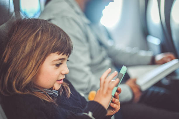 istock Kid on an airplane using a cellphone to play games while traveling with family 1495101094