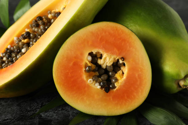 istock Ripe papaya with leaves on black smokey background 1495101140