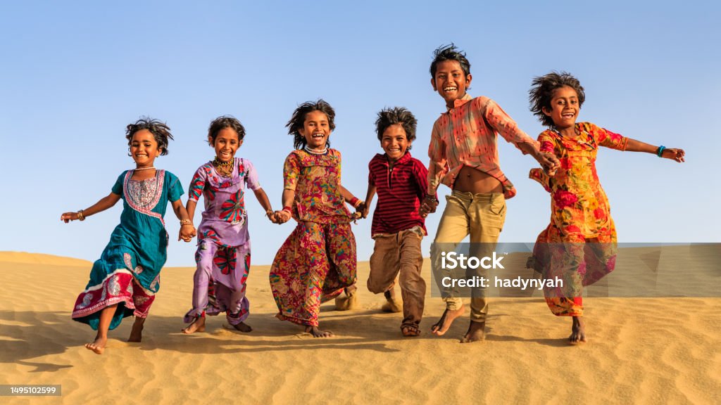 Group of happy Indian children running across sand dune, India Group of happy Indian children running across sand dune - desert village, Thar Desert, Rajasthan, India. Running Stock Photo