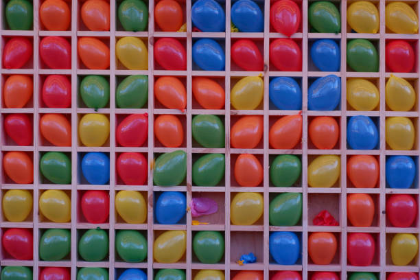 fléchettes aériennes. boules gonflables multicolores dans des cellules pour jouer aux fléchettes. ballons multicolores sur le plateau pour jouer aux fléchettes. fond coloré, couleurs arc-en-ciel. - rubber dart photos et images de collection