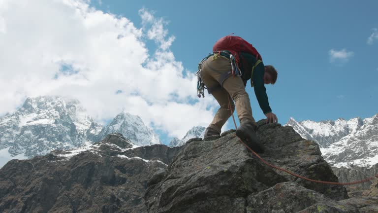 Mountain climber ascends final steps of summit, on belay