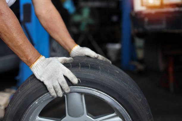 istock Man technician car mechanic hands in uniform holding tire for replacement or changeing at repair garage. Concept of car center repair service. 1495105061