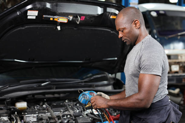 istock Mechanic in half uniform checking car air conditioning system refrigerant recharge, leak detection, fill refrigerant service.Concept of car center repair service. 1495105804
