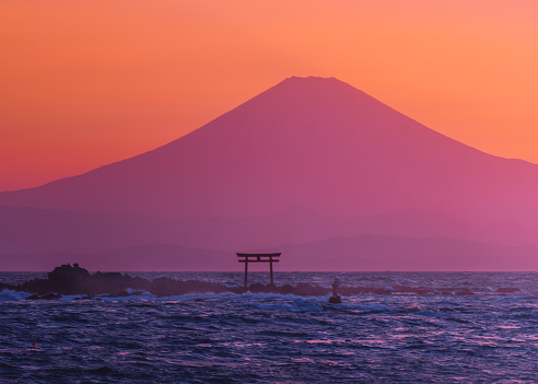 at sunset, the colorful silhouette of Mount Fuji and the torii of the shrine across the Shonan Sea in the evening.A photo taken from the coast of Zushi Hayama , Yokosuka City, Kanagawa Prefecture, Japan.