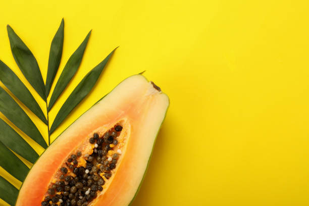 istock Papaya and palm leaf on yellow background 1495105984