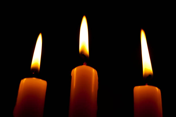 istock Beautiful image with 3 lighted candles with white and yellowish flames on a black background 1495107726