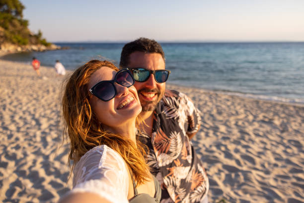 istock Young Caucasian couple, taking selfie on the beach during sunset 1495111482