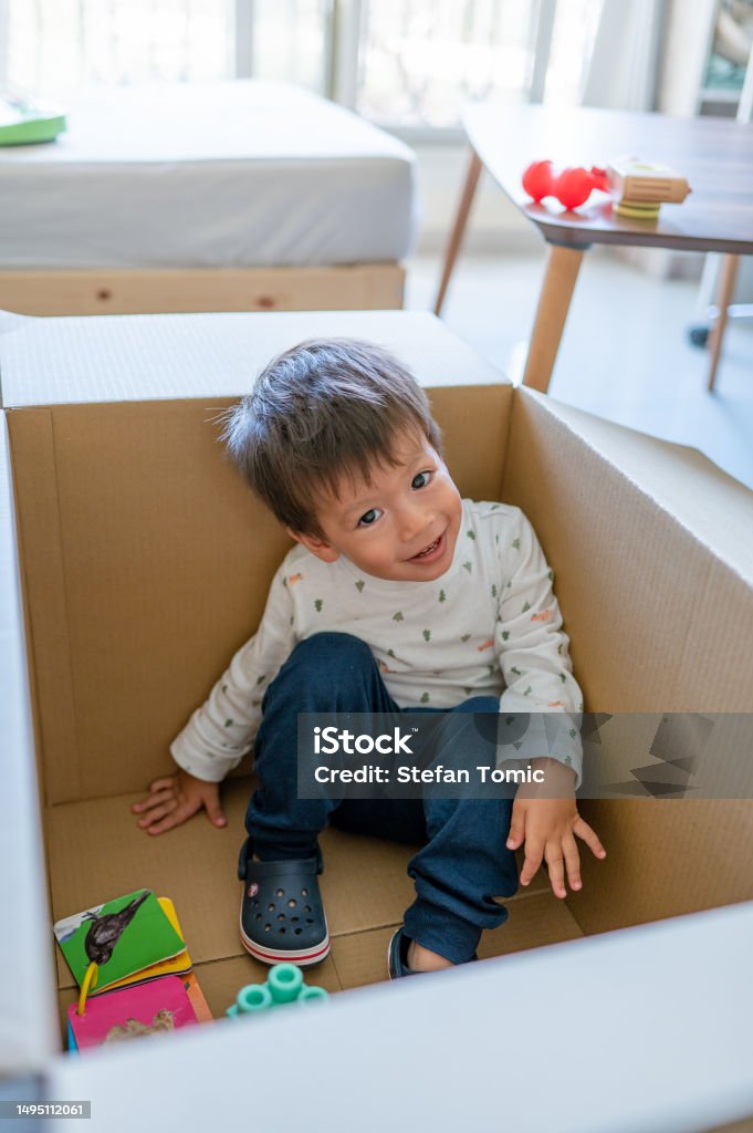 Ein Kleinkind spielt fröhlich mit Spielzeugautos in einer großen Lieferbox und verwandelt es in eine Welt der Fantasie und des endlosen Spaßes - Lizenzfrei Kind Stock-Foto Ein Kleinkind spielt fröhlich mit Spielzeugautos in einer großen Lieferbox und verwandelt es in eine Welt der Fantasie und des endlosen Spaßes - Lizenzfrei Kind Stock-Foto