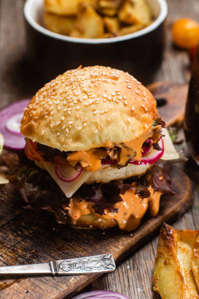 istock Appetizing burger with chicken cutlet on a wooden board 1495113895