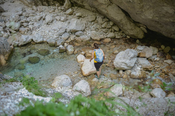 istock Woman crossing a small stream of river 1495116502