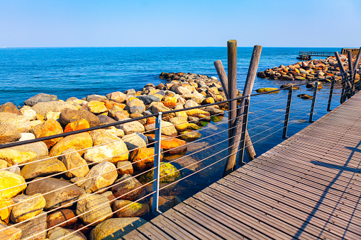 Wooden footbridge along the sea of the rocky coast