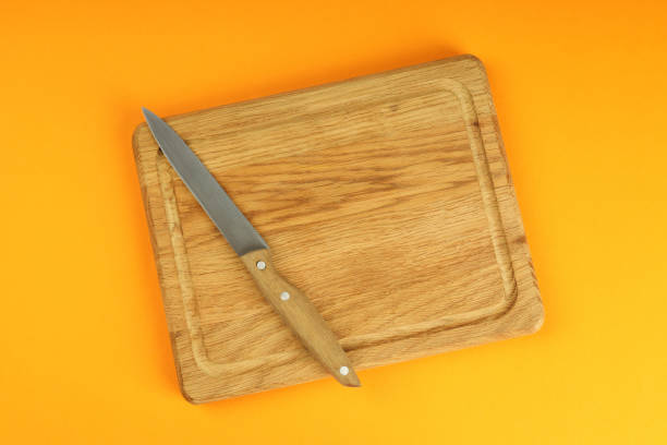 istock Cutting board with knife on orange background 1495121546