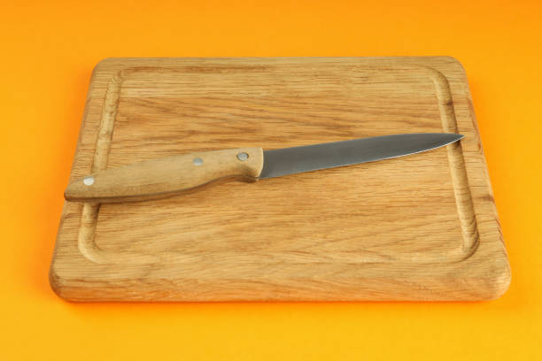 istock Cutting board with knife on orange background 1495121695