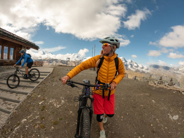 istock Young woman mountain biker pushes bicycle up trail 1495124732