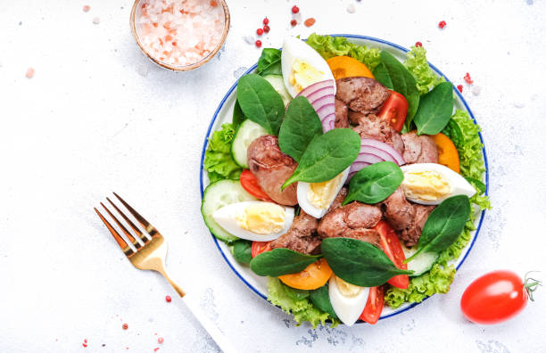 istock Perigord salad with roasted chicken liver, red tomatoes, cucumbers, boiled eggs, lettuce and spinach. Black kitchen table background, top view 1495125307