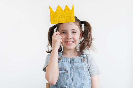 Beautiful little girl with paper crown posing on white background