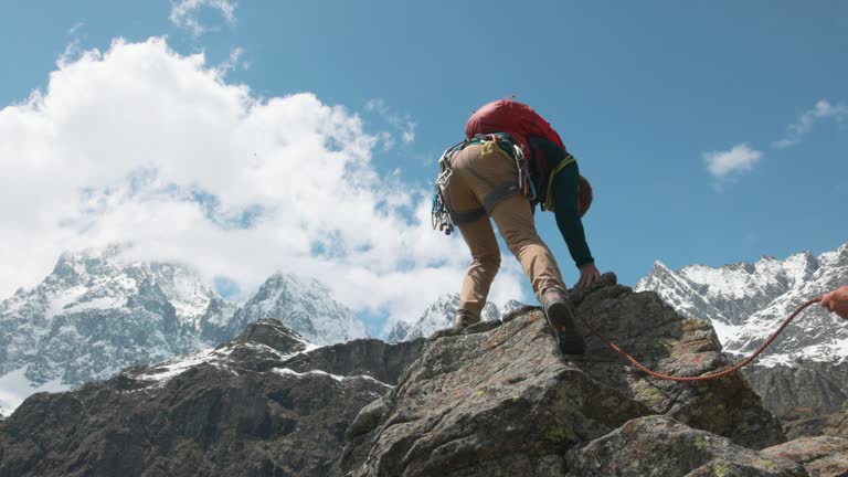 Mountain climber ascends final steps of summit, on belay