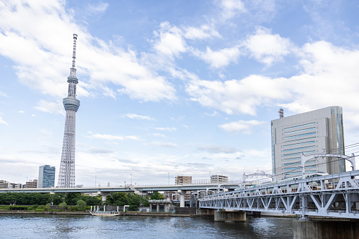 Tokyo, Japan - May 8, 2023 : Landscape of Tokyo Skytree Tower with cloudy sky and railway skytrain crossing the river
