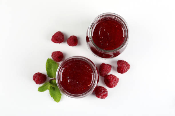 Jars of raspberry jam with ingredients on  white background
