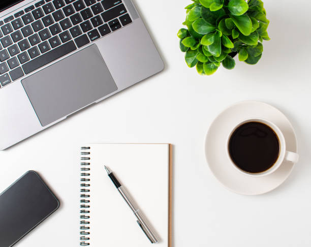 istock Laptop and coffee cup on a white table in the office. Working concept using technology, smartphones, notebook, internet. Crop, Close up, top view white background 1495129559