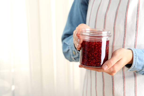 istock Woman holding jar of raspberry jam in hands, space for text 1495129598