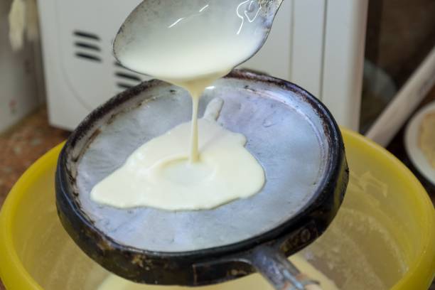 istock Closeup of a spoon with dough pouring into a pan 1495130322