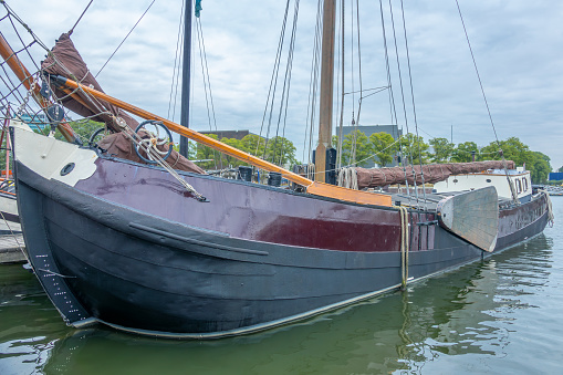 Netherlands. Cloudy day on the Amsterdam canal. Old cargo sailing ship at the pier