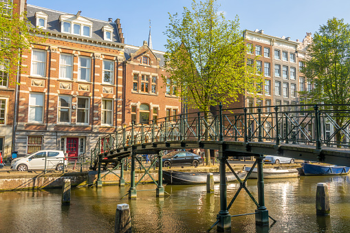 Netherlands. Sunny summer day in Amsterdam. Old iron footbridge across the canal