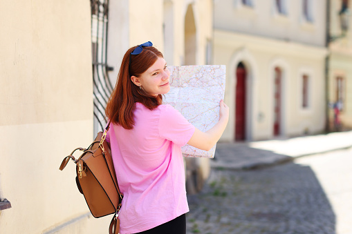 girl tourist looking at the map on the street of european city, travel to Europe