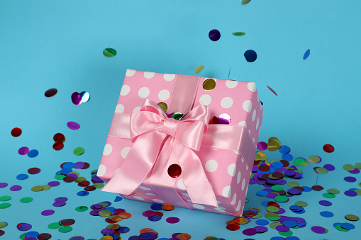 Pink gift box and glitter on blue background