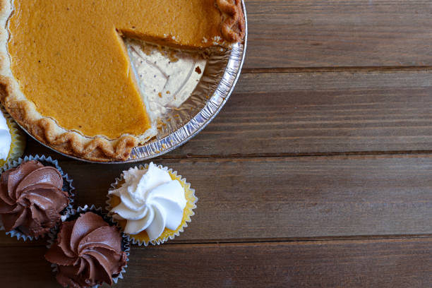 A pumpkin pie and cupcakes on a wooden table