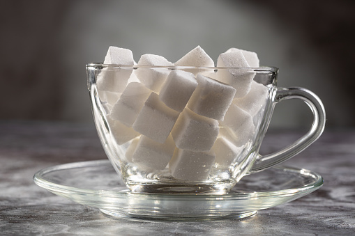 White sugar cubes in transparent glass cup.