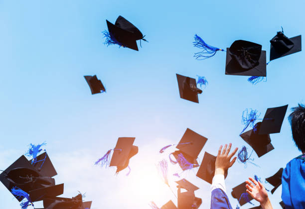 istock Graduating students hands throwing graduation caps in the air 1495139659