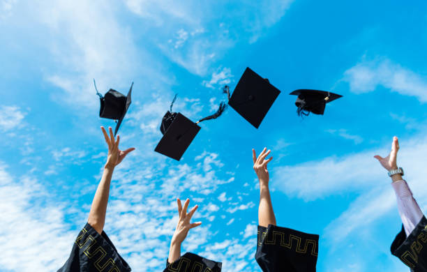 istock Four graduates throwing graduation hats in the air 1495139784