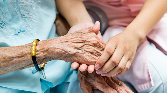 Young woman hand touch and hold an old woman's wrinkled hands