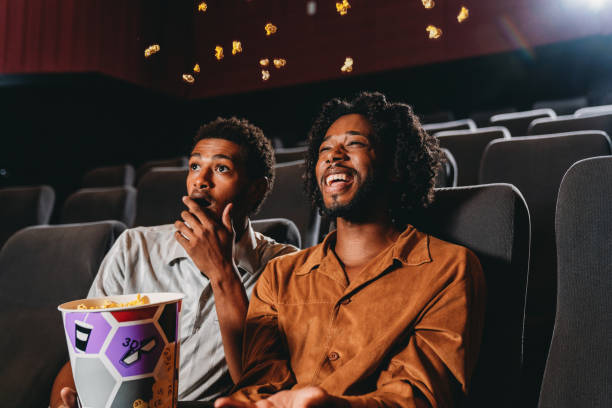 A couple is watching a movie at the movie theatre A couple is watching a movie at the movie theatre. They are eating popcorn together. gay comedian stock pictures, royalty-free photos & images