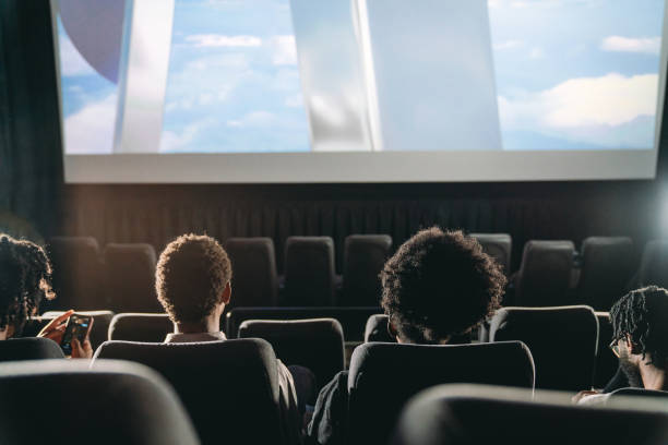 Rear view of people watching a movie at the movie theatre stock photo