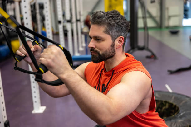 istock Muscular man doing exercise with TRX, functional workout for body at gym. 1495146968