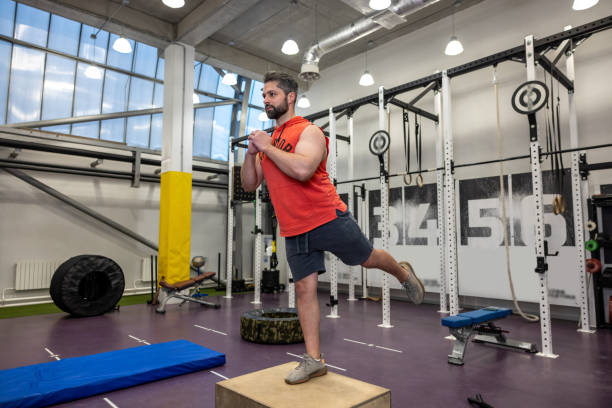 istock Young strong man doing workout with wooden box step up in gym gym. 1495146992