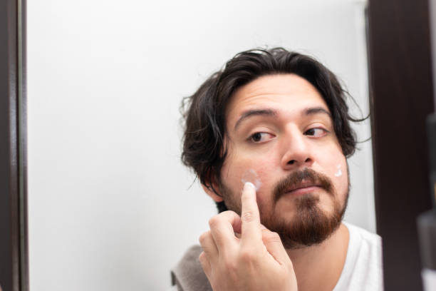 istock Portrait of man putting moisturizer on her face front mirror with copy space 1495147462